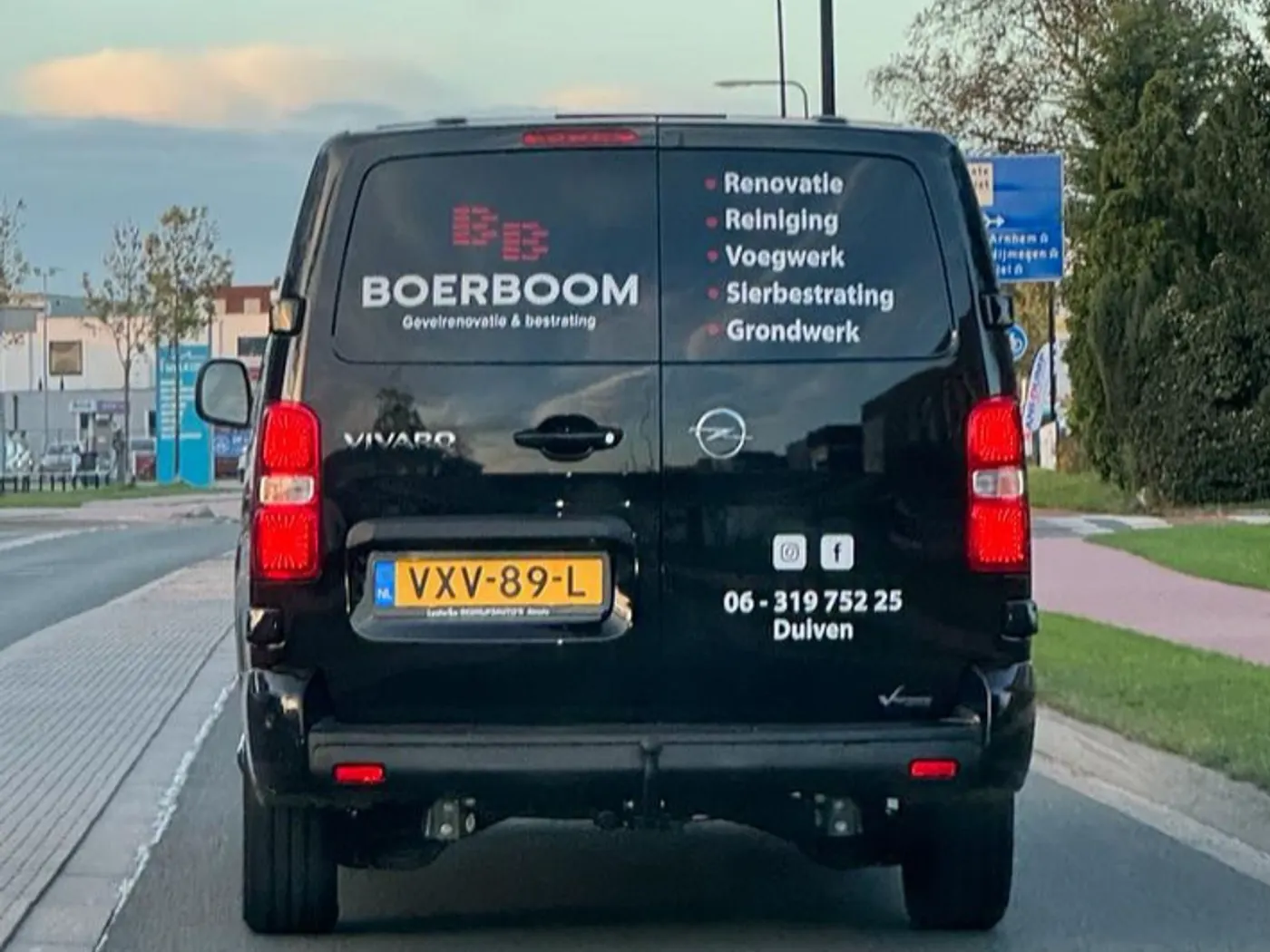De zwarte bus van Boerboom op straat in Duiven, met telefoonnummer op de achterklep