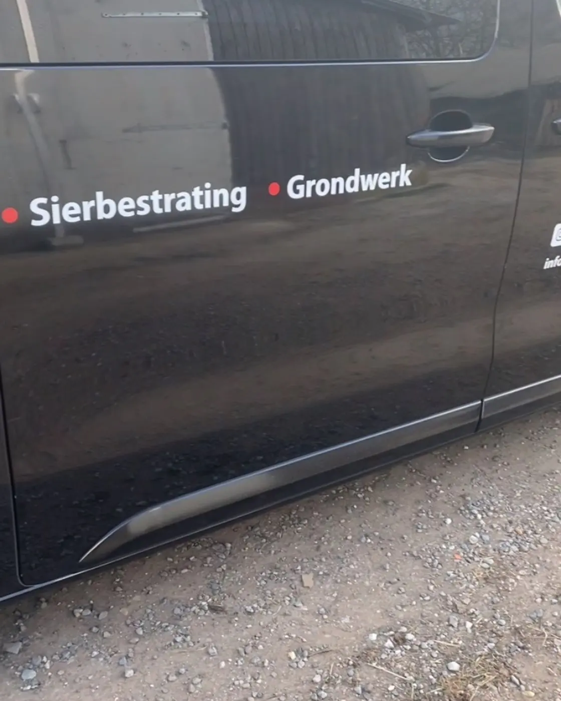 Zijkant van de zwarte bus met de tekst Sierbestrating en Grondwerk