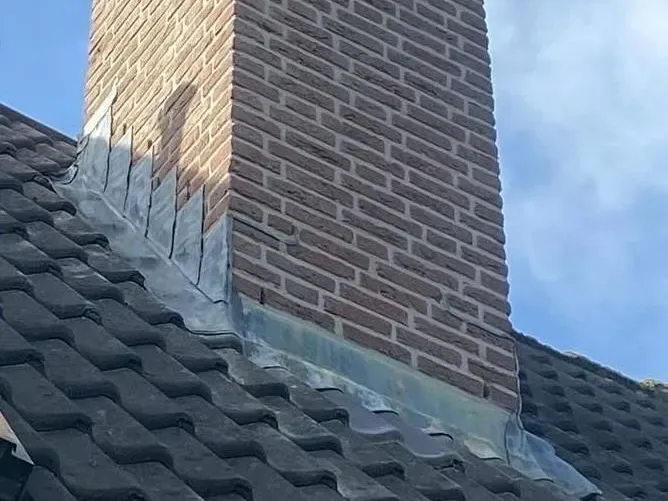 Gemetselde schoorsteen met nieuw lood op een pannendak