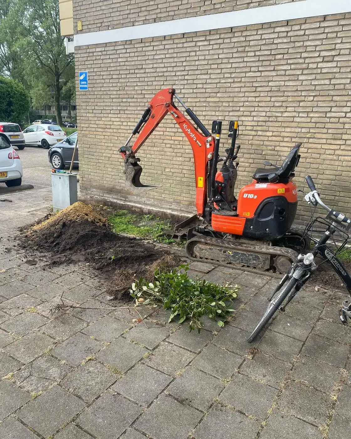 Oranje minigraver bij het grondwerk voor een nieuwe tuin