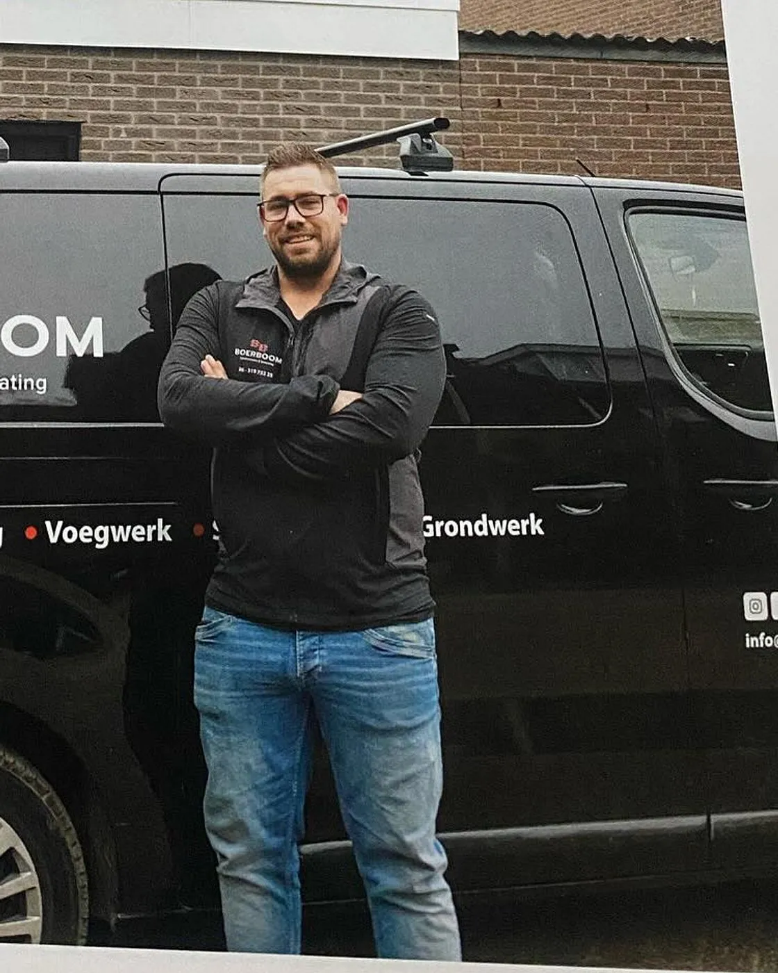 Jeroen Boerboom naast zijn zwarte bedrijfsbus met de opdruk Boerboom Gevelrenovatie & Bestrating