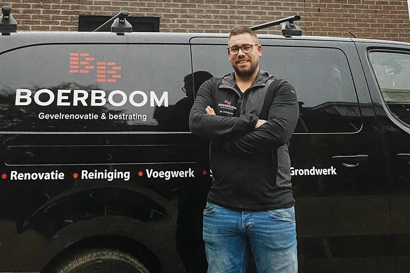 Jeroen Boerboom met de armen over elkaar voor zijn zwarte bedrijfsbus met de belettering Boerboom Gevelrenovatie & bestrating