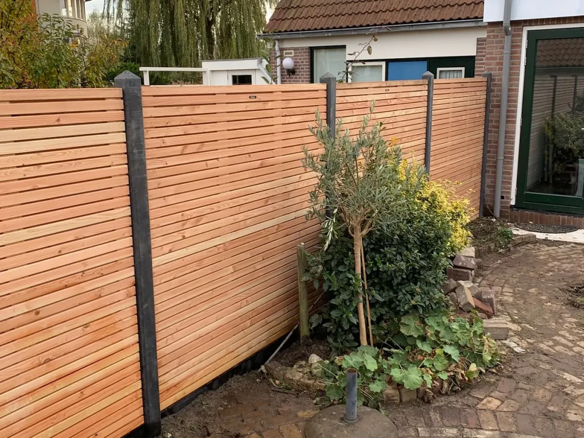 Nieuwe houten schutting met liggende planken en een klinkerpad