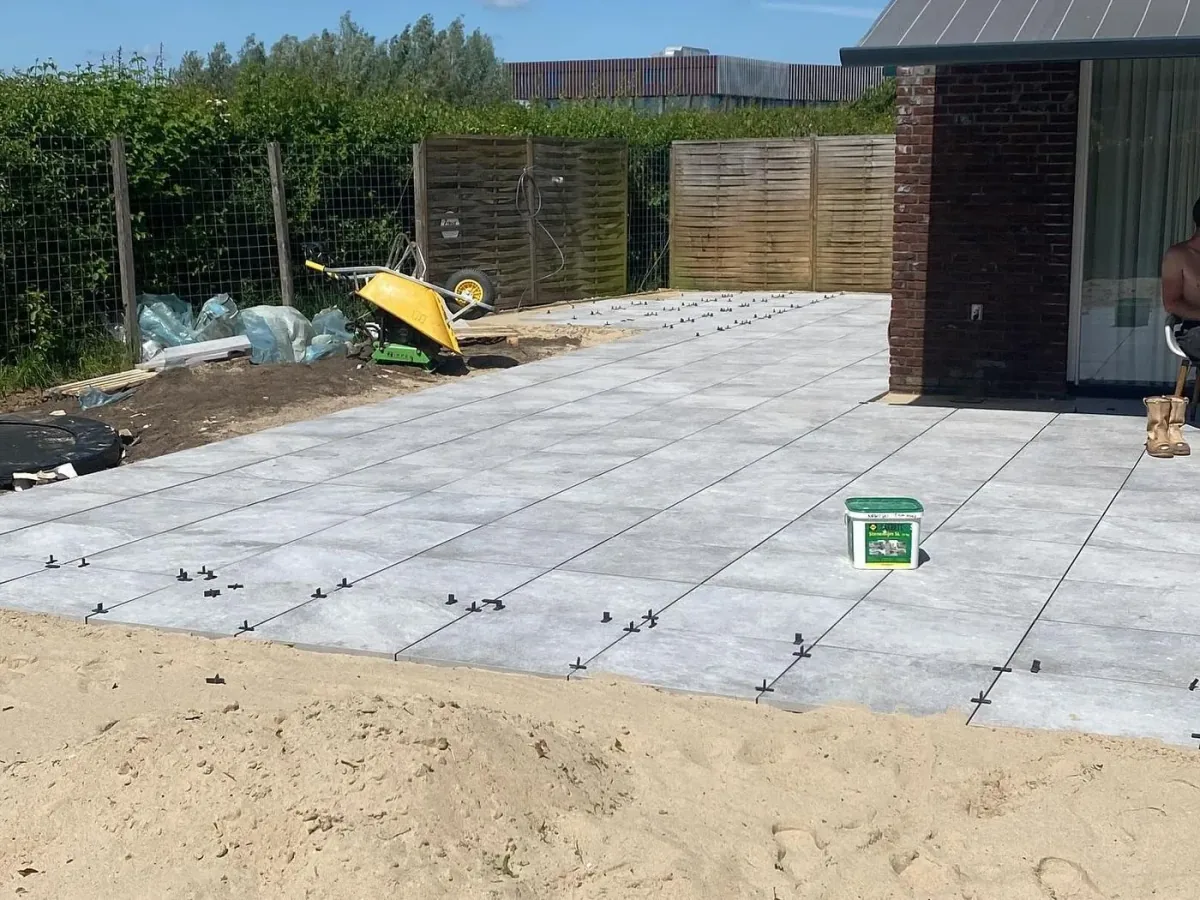 Terras van grote grijze tegels in aanleg op een zandbed