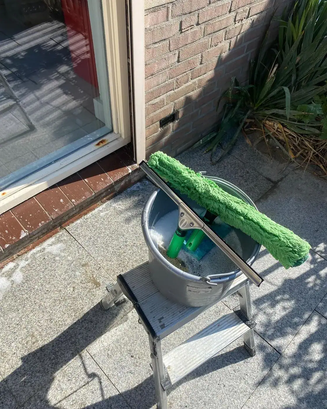 Emmer met raamwisser op een vensterbank na de gevelwerkzaamheden