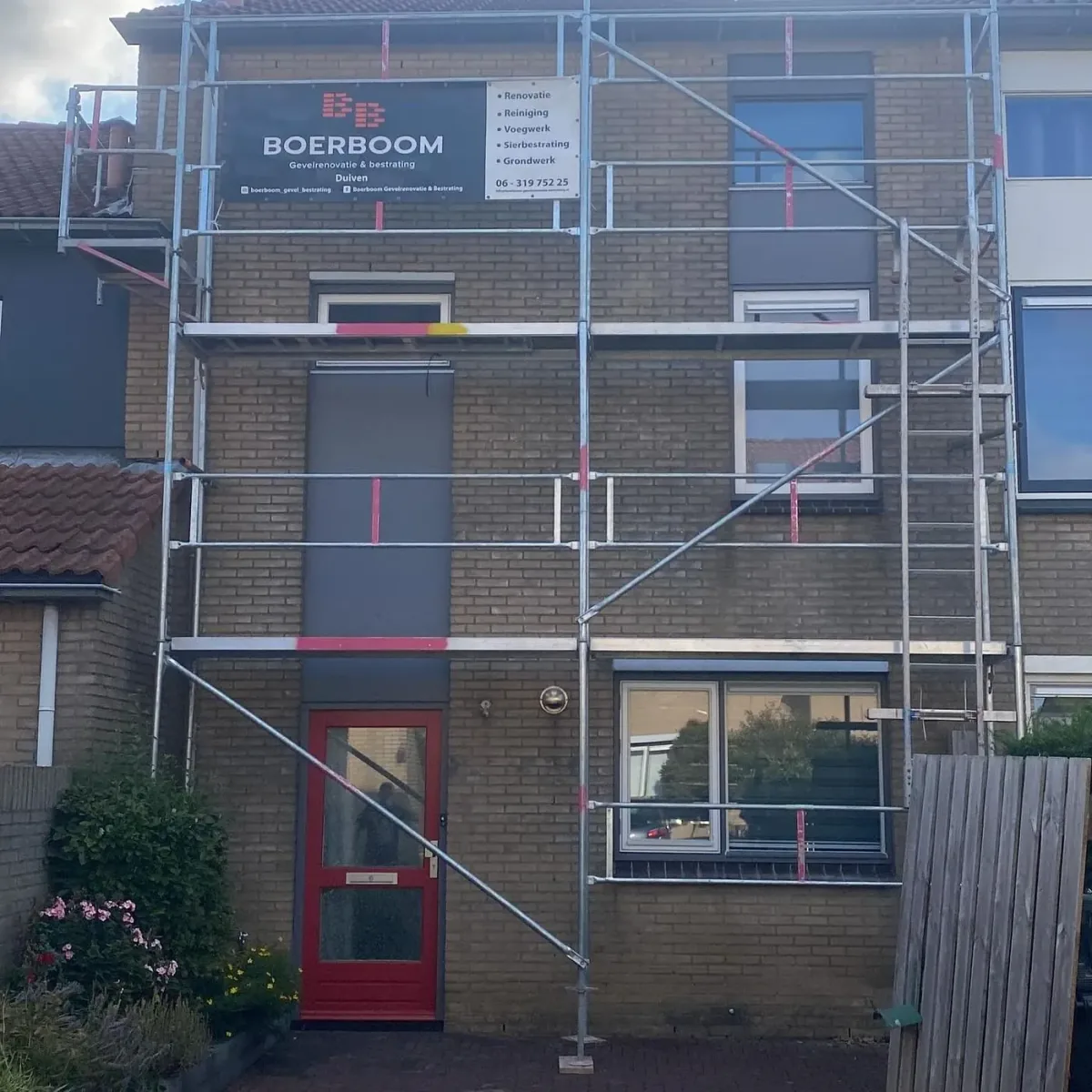Steiger met het bord van Boerboom tegen een woning met een rode voordeur