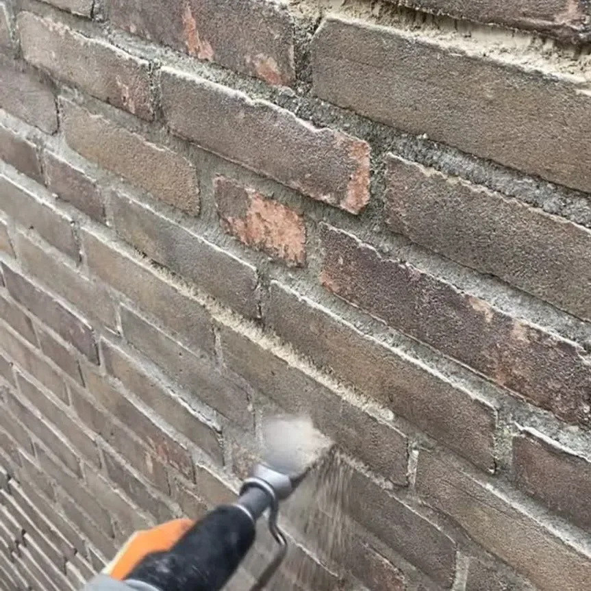 Oude voeg wordt uit een bakstenen muur gehakt