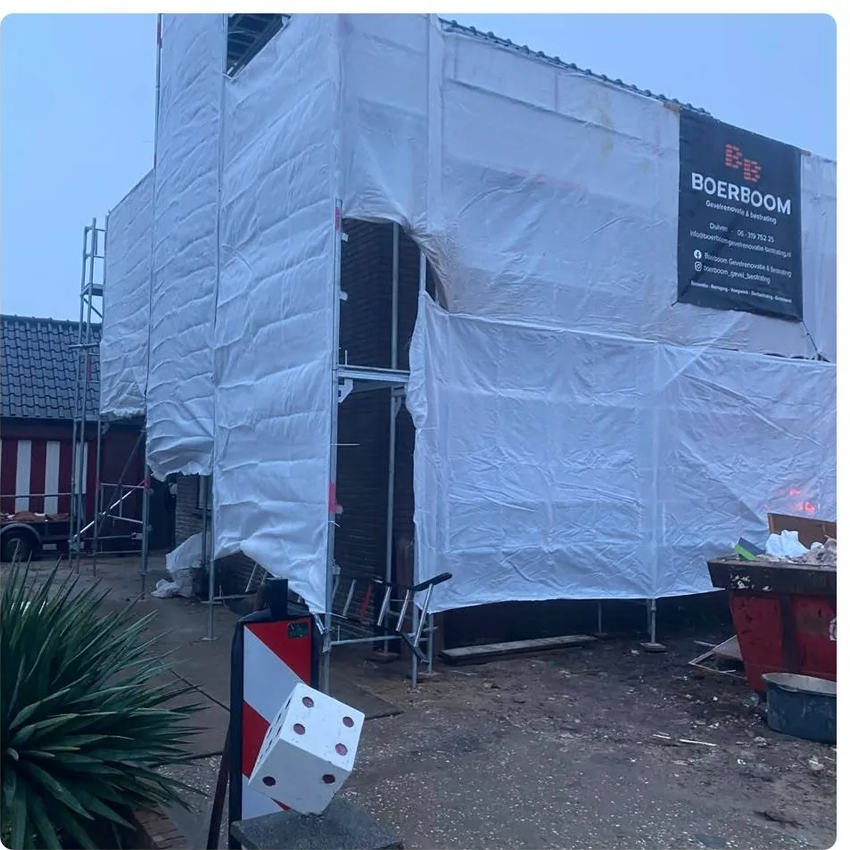 Woning volledig ingepakt in de steigers met het bord van Boerboom en een container ervoor