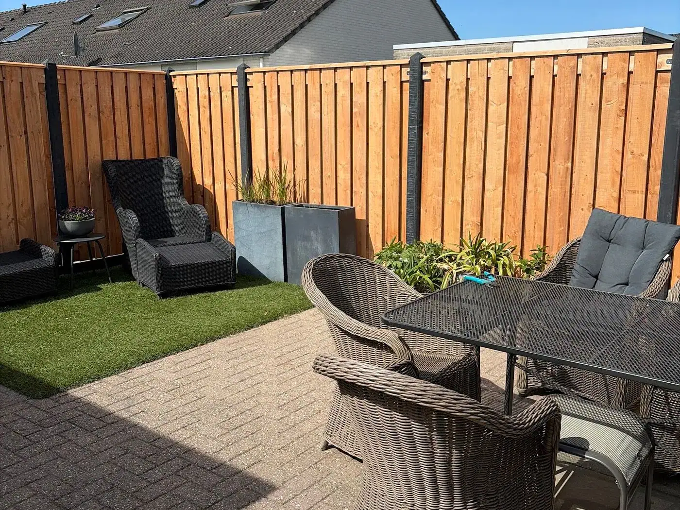 Achtertuin met terras, kunstgras en een nieuwe houten schutting
